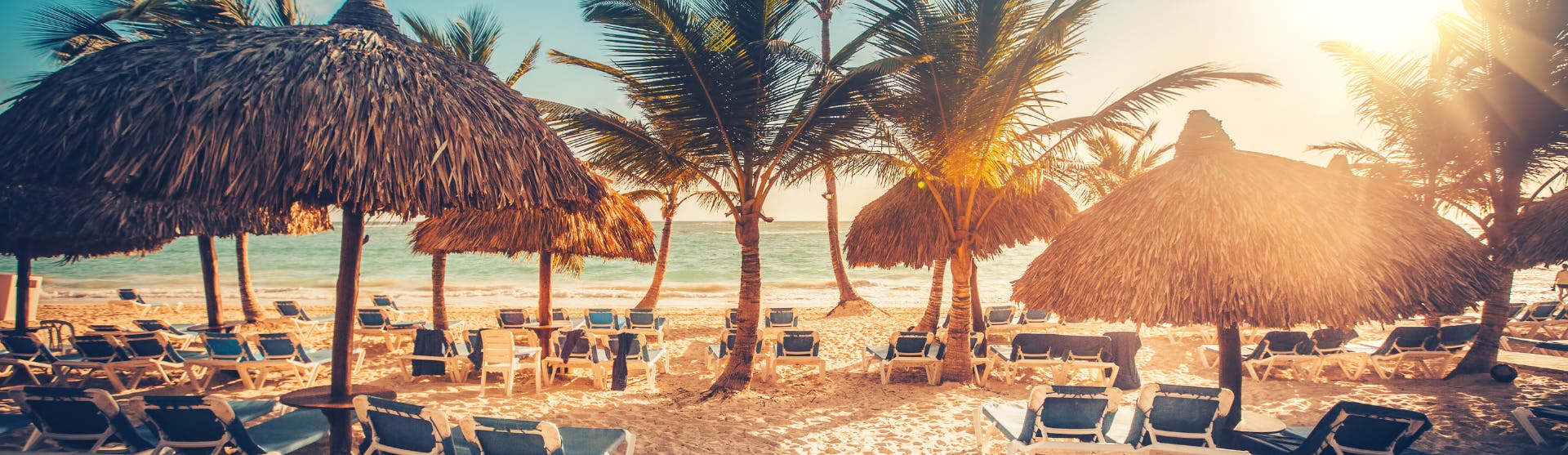 Kryssa i östra Karibien och upplev vackra stränder och kulturella pärlor. Bilden visar en strand med solstolar framför vattnet.