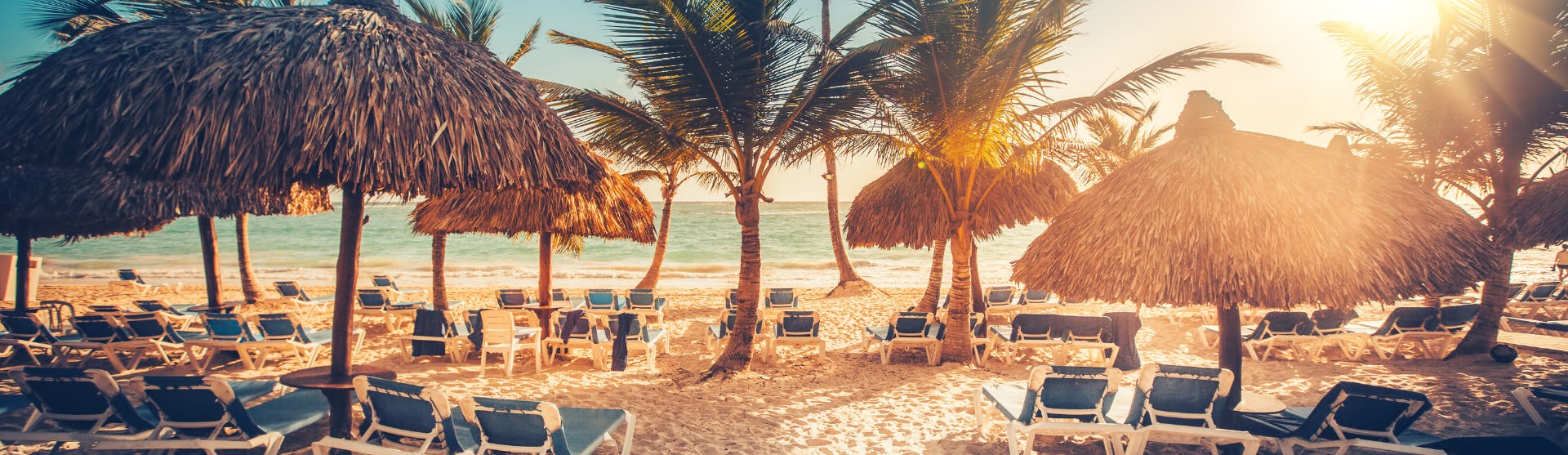 Kryssa i östra Karibien och upplev vackra stränder och kulturella pärlor. Bilden visar en strand med solstolar framför vattnet.