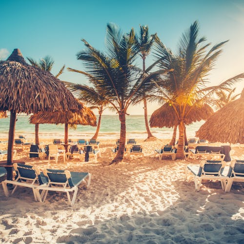 Kryssa i östra Karibien. På bilder ser vi en strand med solstolar och havet i bakgrunden.