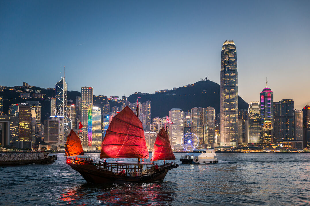 Bilden visar ett upplyst segelfartyg utanför Hong Kong kvällstid