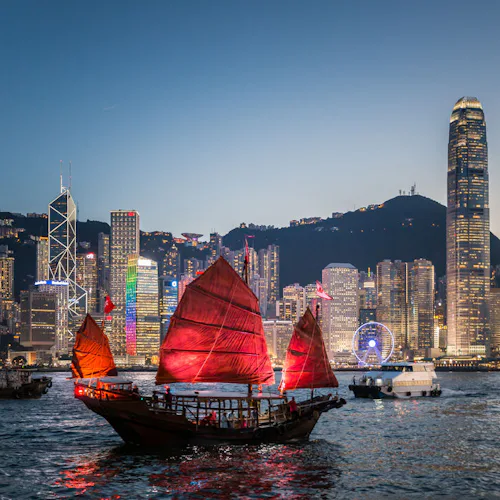 Bilden visar ett upplyst segelfartyg utanför Hong Kong kvällstid