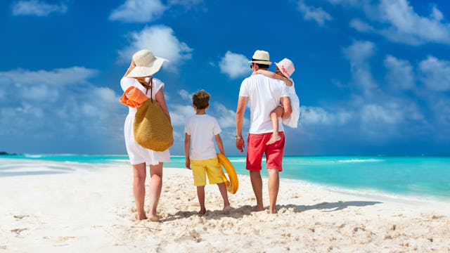 Din semester i Karibien. I bilden står en familj på en sandstrand och tittar ut över havet.