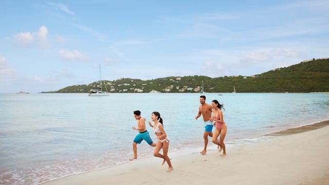 Bilden visar en familj som springer på en strand.