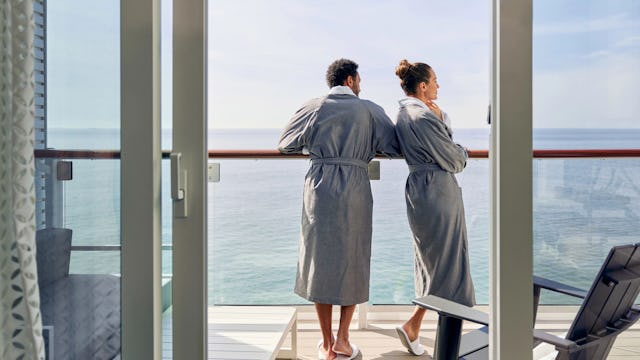 Två personer står på sin balkong till sin hytt i morgonrock och tittar ut över vattnet. Hitta lyxkryssningar medelhavet här med all inclusive.