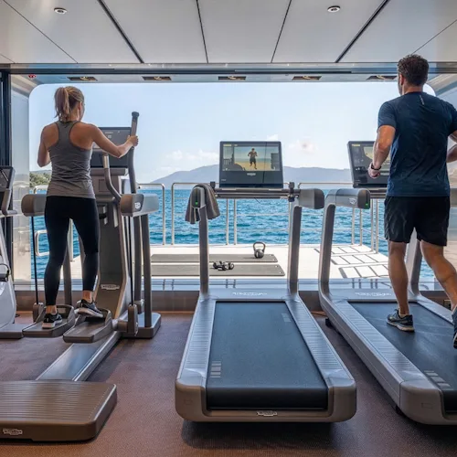 Bilden visar två personer som tränar på ett gym ombord på fartyget Emerald Kaia