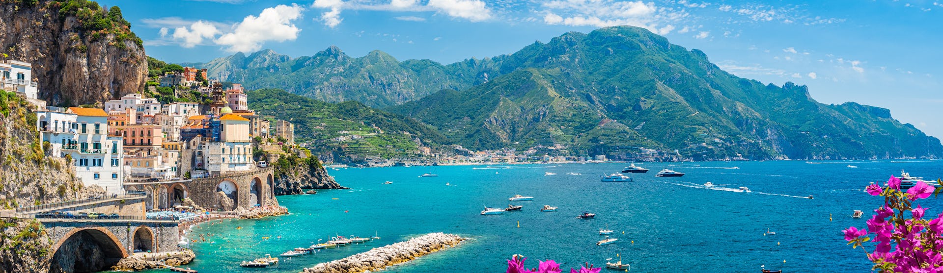 Kryssa runt Medelhavet. Låt en Medelhavskryssning bli din nästa semester fylld av kultur, matglädje och spännande destinationer. Bilden visar Italiens vackra kust med hus, berg och blommor.