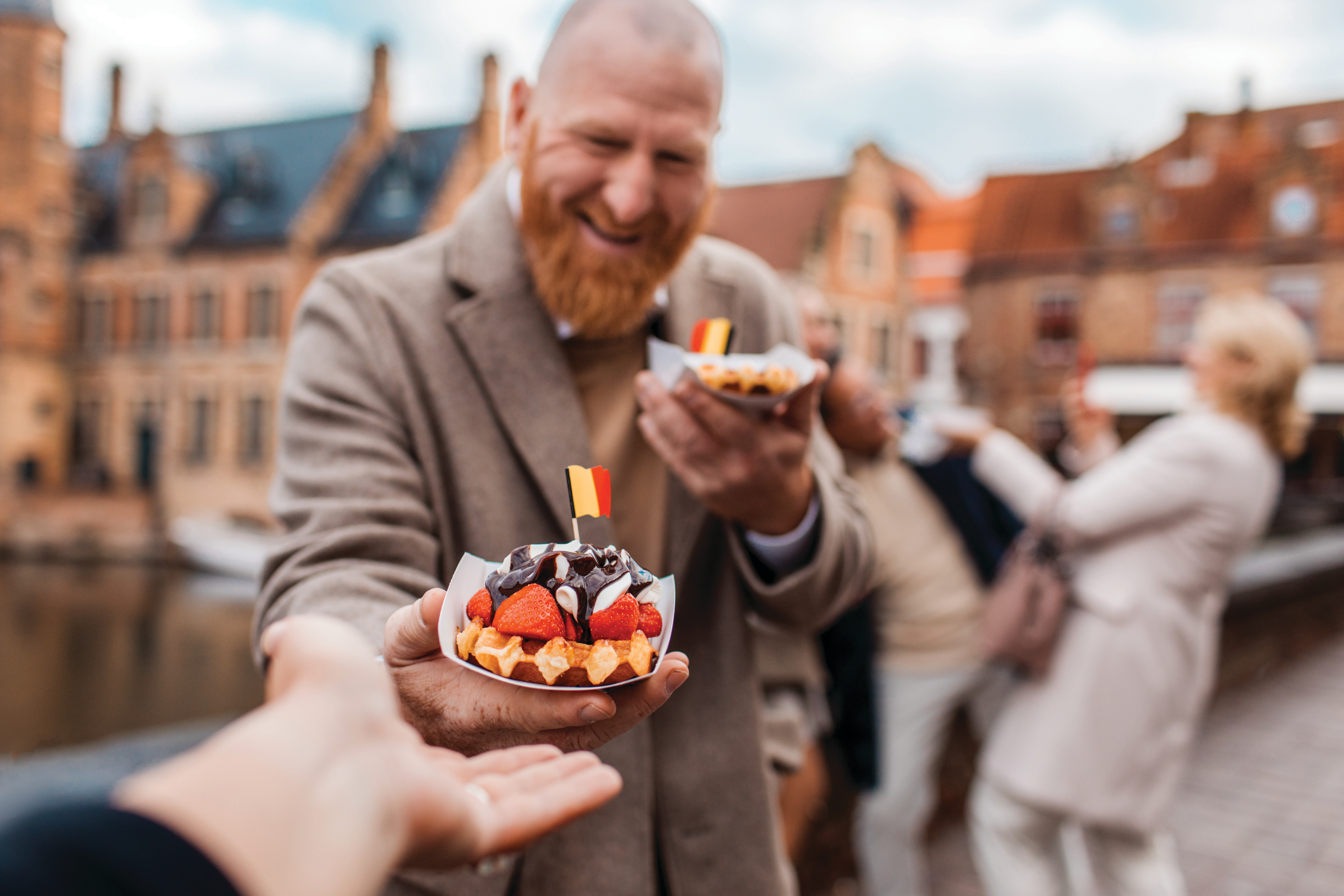Upplev smaker från Norra Europa på en kryssning. Bilden visar en person som håller fram en belgiskvåffla.