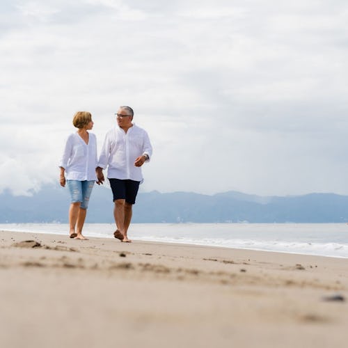Bilden visar två personer som går på en strand.