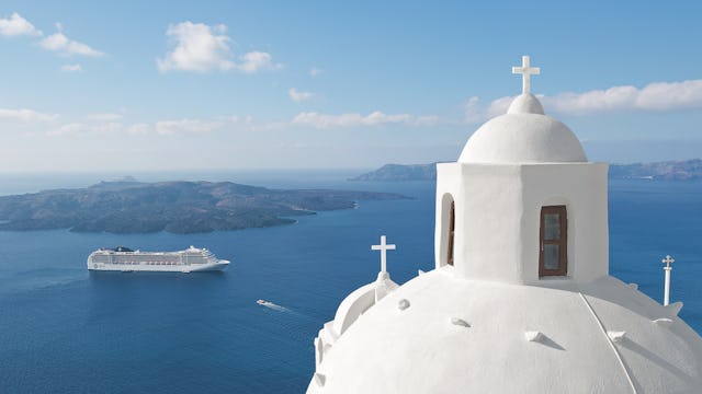 Boka din nästa kryssning hos Cruise Market. Bilden visar ett fartyg som åker i Grekland med vita byggnader i förgrunden.