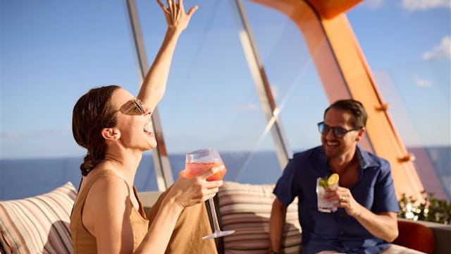Bilden visar två personer som sitter och tar en drink på Celebrity Apex Magic Carpet.