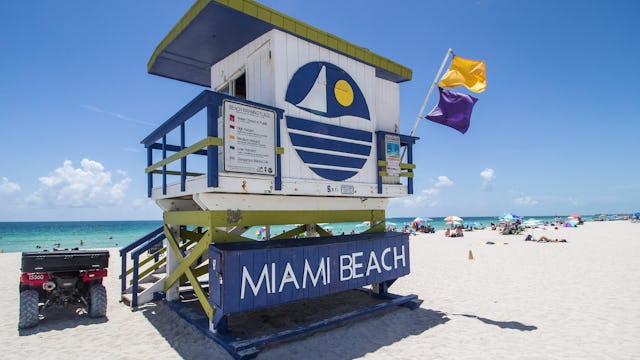 Besök Miami Beach innan din kryssning. På bilden syns ett av vakttornen på Miami Beach med strand och vattenkant framför.