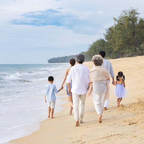 Åk på en generationskryssning med hela familjen samlad. Bilden visar en stor familj som går på en strand vid vattenkanten.