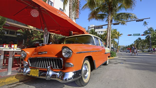 Besök little Havana i Miami innan din kryssning från Miami. Bilden visar en gammaldags Amerikansk bil i en orangefärg som står på en gata i Miami med palmer i bakgrunden.