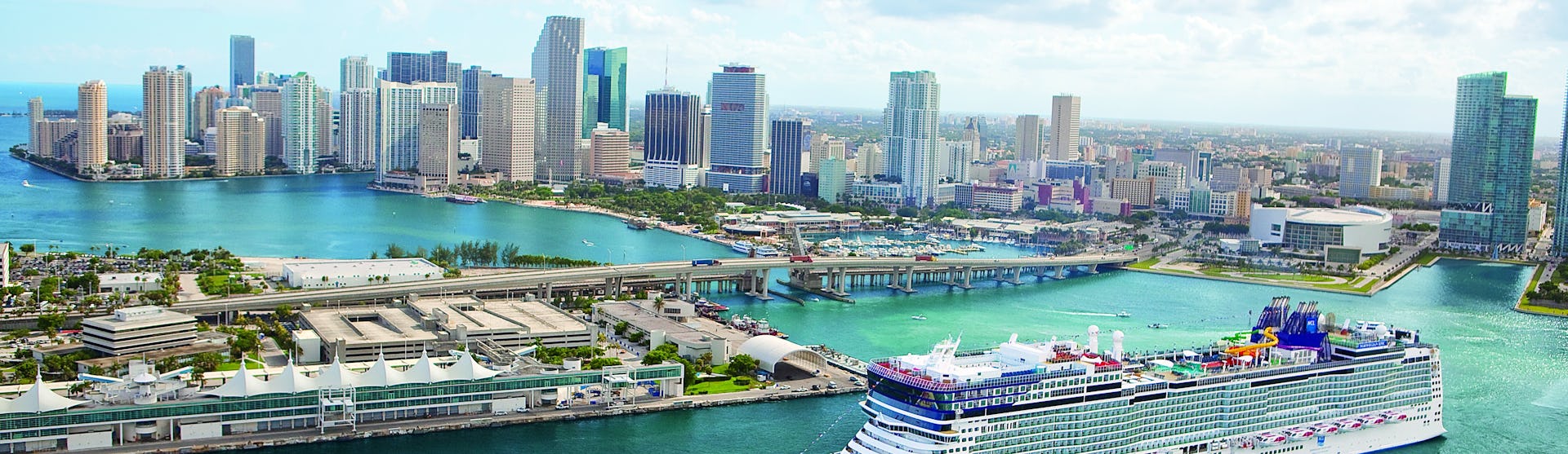 Kryssa från Miami, Florida. Bilden visar ett fartyg som åker in vid Miamis hamn med skyskrapor i bakgrunden.