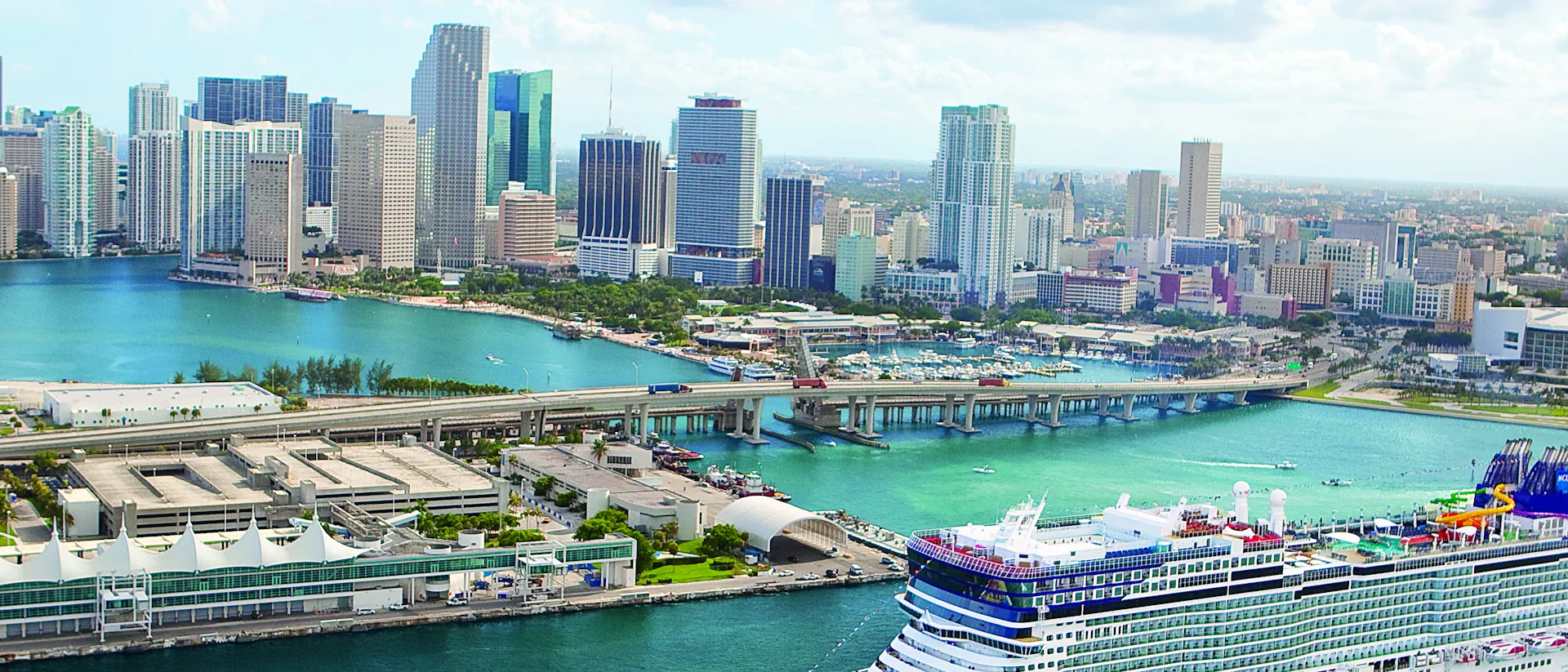 Kryssa från Miami, Florida. Bilden visar ett fartyg som åker in vid Miamis hamn med skyskrapor i bakgrunden.