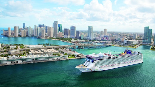 Kryssa från Miami, Florida. Bilden visar ett fartyg som åker in vid Miamis hamn med skyskrapor i bakgrunden.