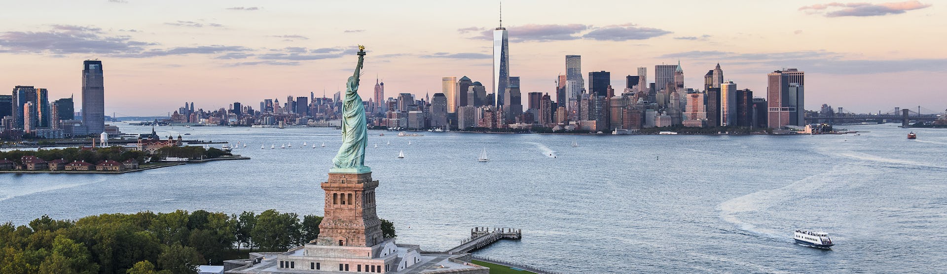 Kryssa till USA eller utgå från USA på din kryssning. Bilden visar en översikt över New York från vattnet med Frihetsgudinnan i förgrunden