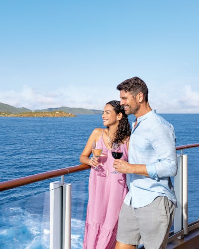 Kryssa över Atlanten från USA. Bilden visar ett par som står vid räcket på ett fartyg och tittar ut över vattnet.