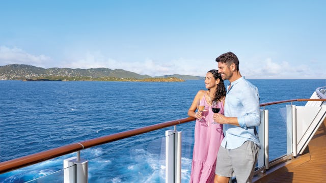 Kryssa över Atlanten från USA. Bilden visar ett par som står vid räcket på ett fartyg och tittar ut över vattnet.