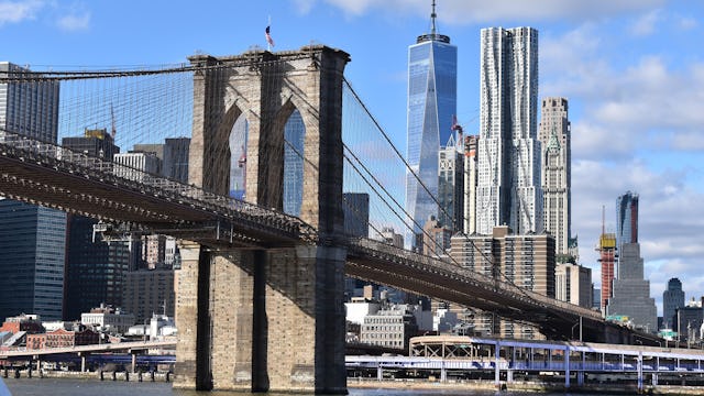 Gå över kända Brooklyn Bridge. Bilden visar en del av Brooklyn Bridge med New Yorks byggnader i bakgrunden.