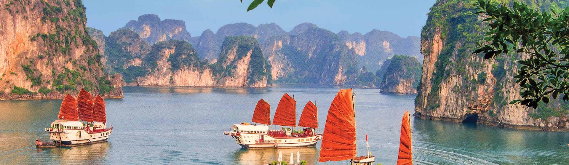 Kryssa runt Asien. En unik semester på ett bekvämt sätt. Bilden är från Vietnam och visar fatyg som seglar mellan berg.