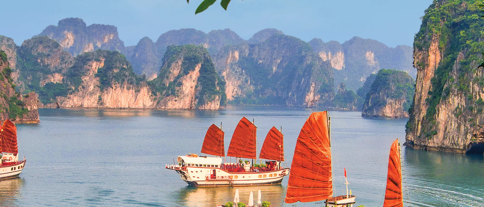 Kryssa runt Asien. En unik semester på ett bekvämt sätt. Bilden är från Vietnam och visar fatyg som seglar mellan berg.