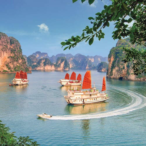 Kryssa runt Asien. En unik semester på ett bekvämt sätt. Bilden är från Vietnam och visar fatyg som seglar mellan berg.