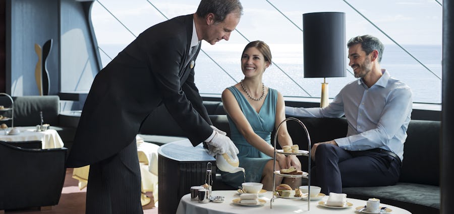 Upplev förstklassig service på en lyxkryssning. Bilden visar en butler som serverar två människor ombord MSC Cruises.