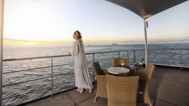 Boka en expeditionskryssning med HX Hurtigruten Expeditions. Bilden visar en person som står vid räcket och tittar ut över havet.