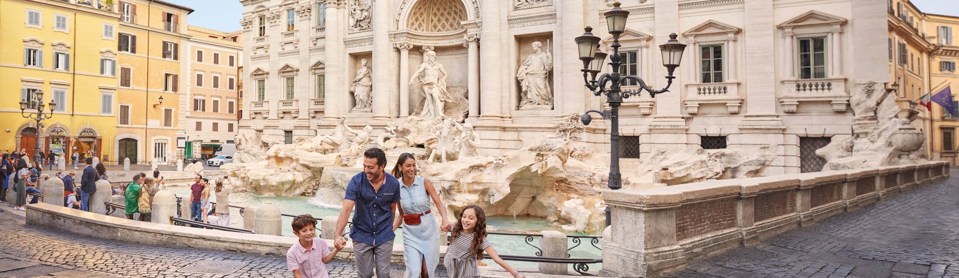 Bilden visar en familj som är på semester i Rom och går framför Fontana Trevi.