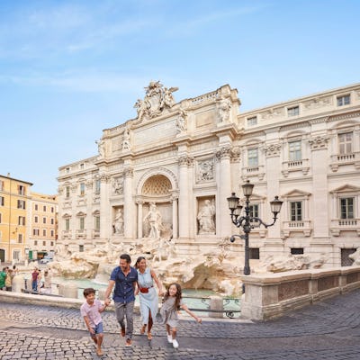 Bilden visar en familj som är på semester i Rom och går framför Fontana Trevi.