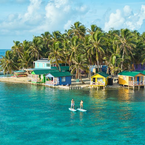Kryssa i västra Karibien. Bilden visar Belize i Karibien och landets klara vatten där ett par åker på paddel board.