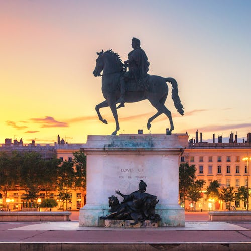 Bilden visar en staty med en människa på en häst i Lyon.