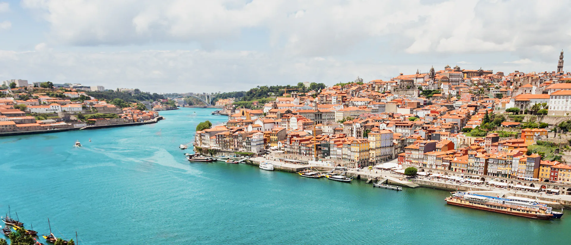 Bilden visar den vackra floden Douro som rinner genom en stad. Upplev en flodkryssning med portugisisk touch längs Douro.