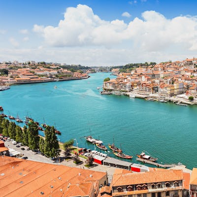 Bilden visar den vackra floden Douro som rinner genom en stad. Upplev en flodkryssning med portugisisk touch längs Douro.