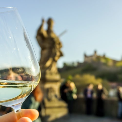 Bilden visar ett glas vitt vin från regionen franken i Tyskland med staden Wurzburg i bakgrunden.