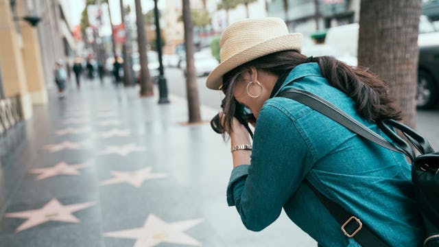 Bilden visar en turist som fotar stjärnorna på trottoaren