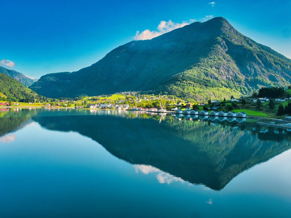 Bild på spegelreflektion av berg i lugnt vatten i Norge