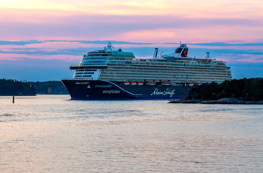 Bilden visar Mein Schiff 7 i hamn i en fantastisk solnedgång.