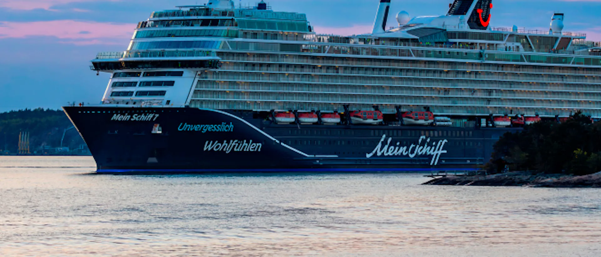 Bilden visar Mein Schiff 7 i hamn i en fantastisk solnedgång.