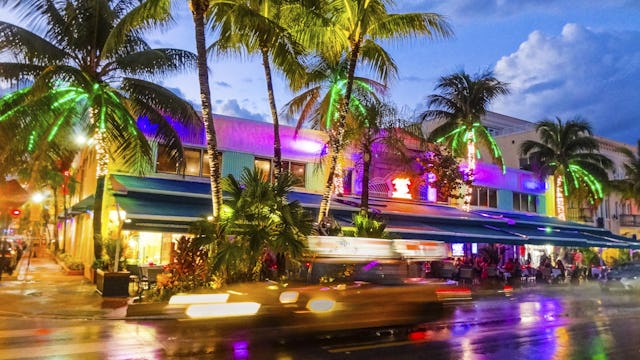 Bilden visar en blurrig bild på en gata i Miami under kvällstid. Upplev Miamis nattliv innan din kryssning.