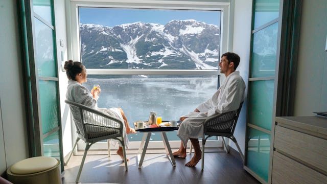Bilden visar ett par som sitter i hytten och njuter av frukost och en vacker utsikt.